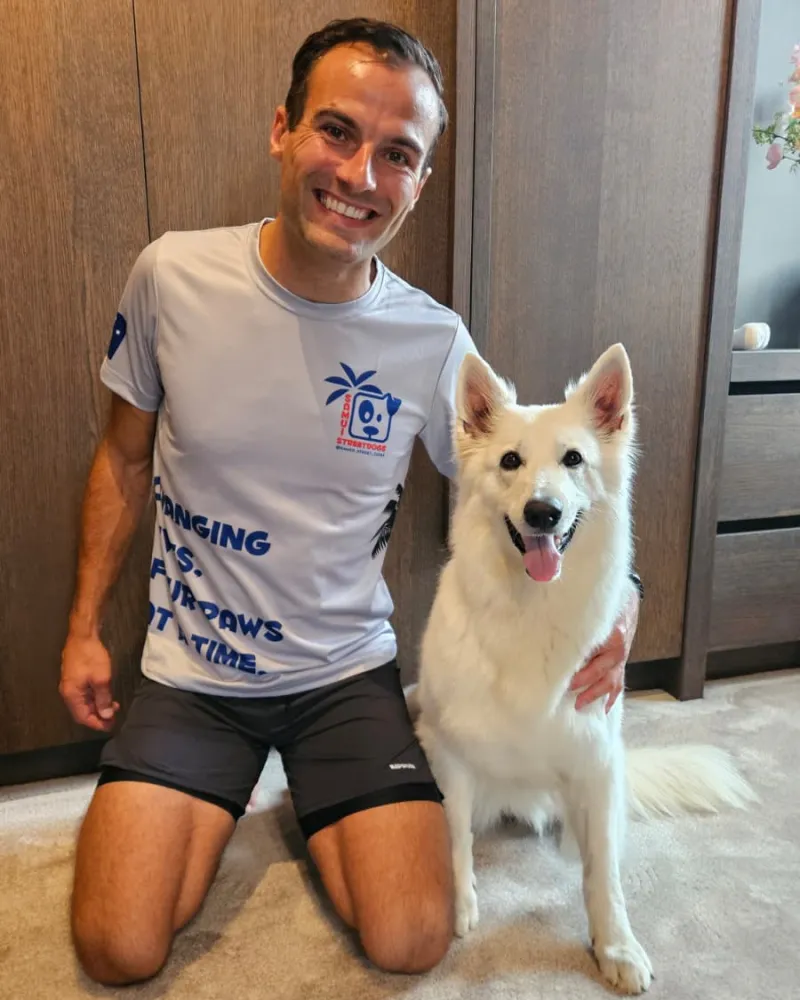 Patrick in zijn Samui Street Dogs-hardloopshirt, geknield naast zijn hond Zoë