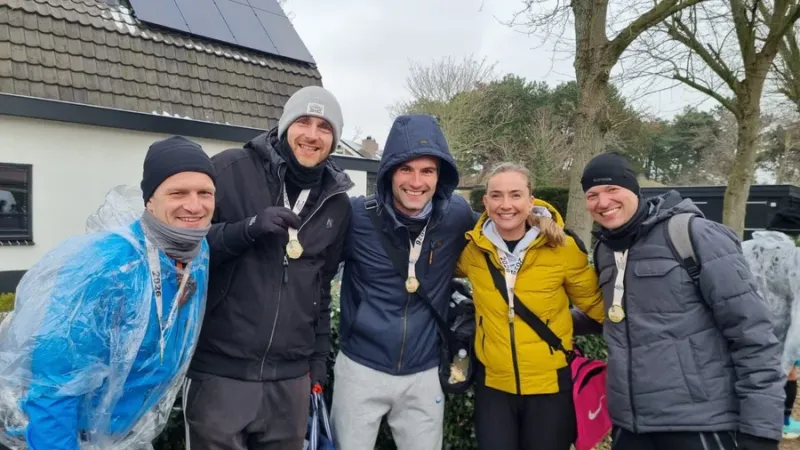 Patrick en medelopers met hun medailles na afloop van een hardloopwedstrijd
